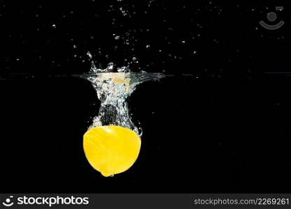 halved lemon falling clean water against black background