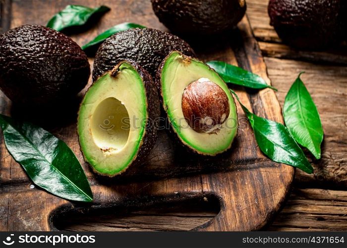 Halves of fresh avocado on a cutting board. On a wooden background. High quality photo. Halves of fresh avocado on a cutting board.