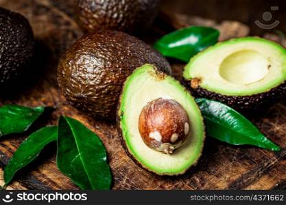 Halves of fresh avocado on a cutting board. On a wooden background. High quality photo. Halves of fresh avocado on a cutting board.