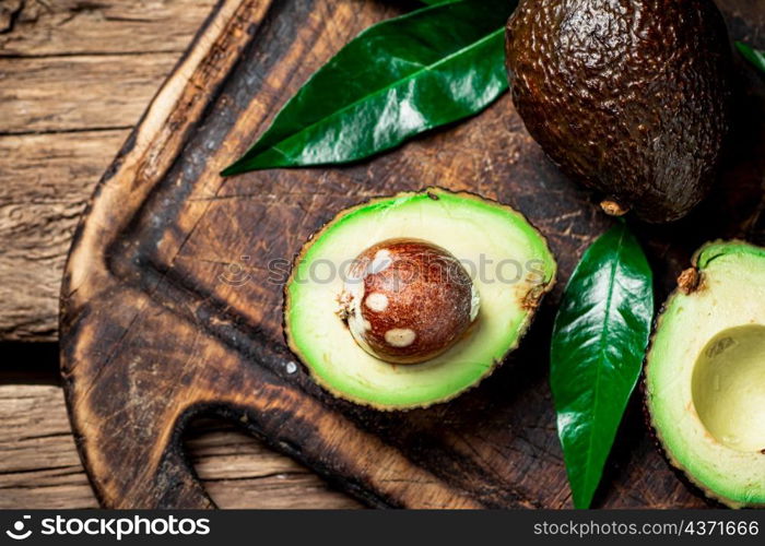 Halves of fresh avocado on a cutting board. On a wooden background. High quality photo. Halves of fresh avocado on a cutting board.