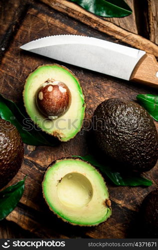 Halves of fresh avocado on a cutting board. On a wooden background. High quality photo. Halves of fresh avocado on a cutting board.