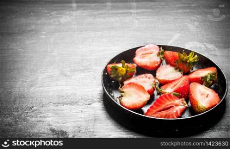 Halves of strawberry in the old plate. On the black wooden table.. Halves of strawberry in the old plate.