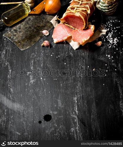 Ham with a hatchet and spices . On the black chalkboard.. Ham with a hatchet and spices .