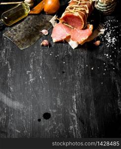 Ham with a hatchet and spices . On the black chalkboard.. Ham with a hatchet and spices .