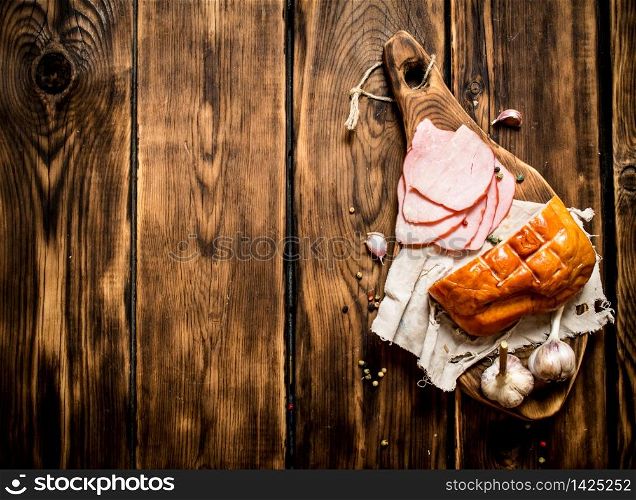 Ham with garlic and spices on the old Board. On wooden background.. Ham with garlic and spices on the old Board.