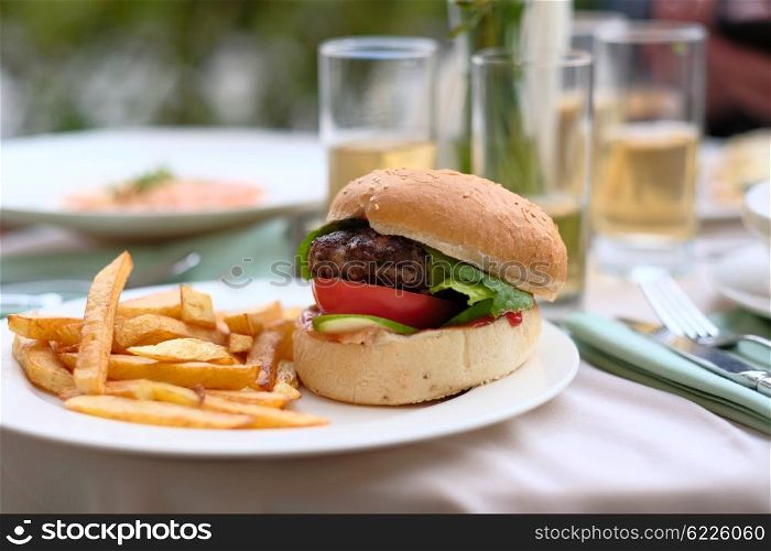 Hamburger and fries at restaurant outdoor table