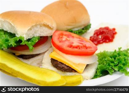 Hamburger And Pickles. Three mini-hamburgers with all the fixings, sliced dill pickle isolated on a white background