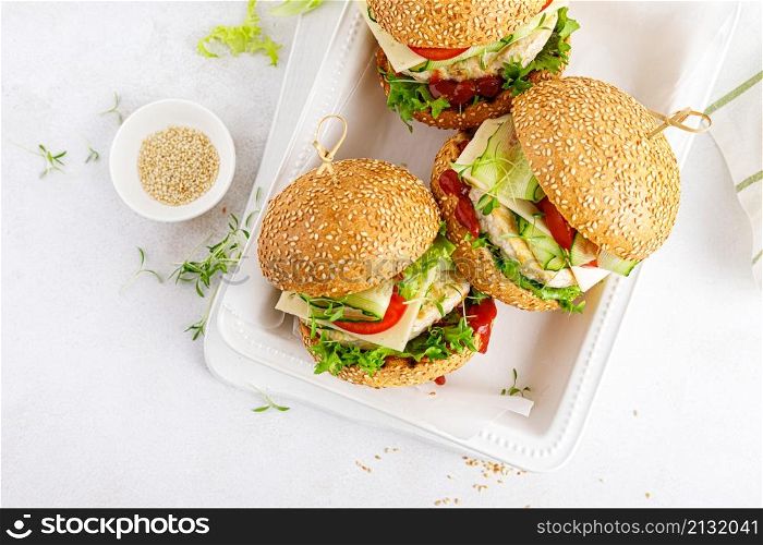 Hamburger with grilled chicken burger, fresh cucumber, tomato, cheese and lettuce. Top view.