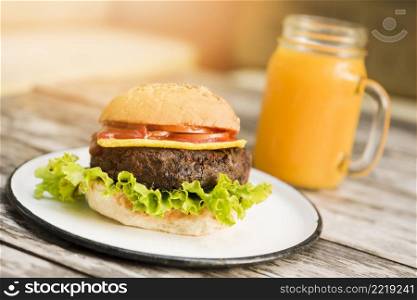 hamburger with tomatoes cheese lettuce served with juice glass wooden table