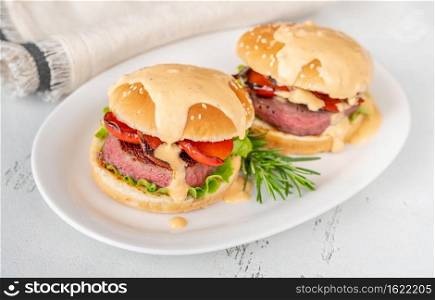 Hamburgers with grilled pepper topped with savory sauce on the white serving plate