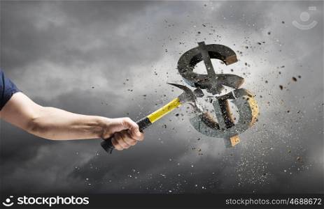 Hammer in hand. Close up of hammer in human hand breaking stone dollar symbol