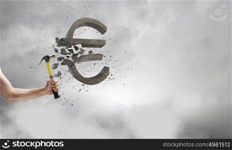 Hammer in hand. Close up of hammer in human hand breaking stone euro symbol