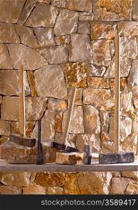 Hammer mason tools of stonecutter masonry work in a contruction stone wall