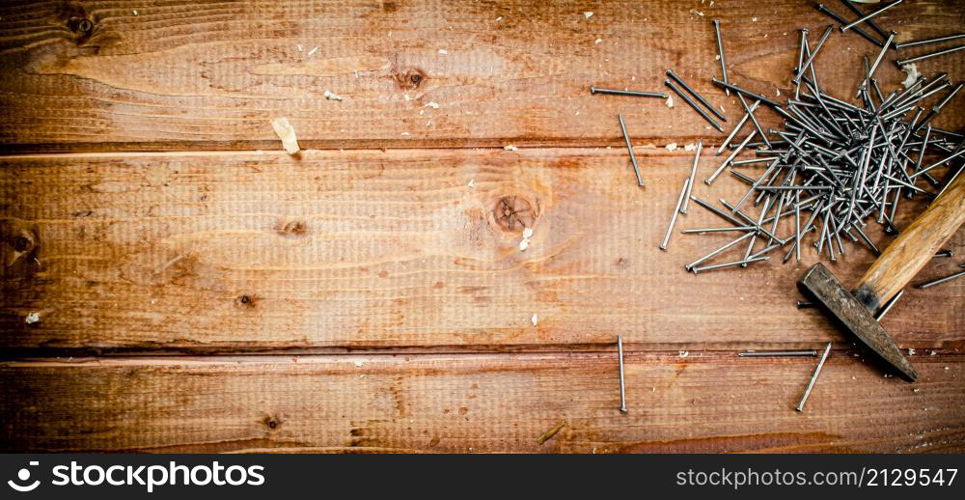 Hammer with a bunch of nails on the table. On a wooden background. High quality photo. Hammer with a bunch of nails on the table.