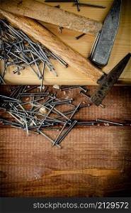 Hammer with a bunch of nails on the table. On a wooden background. High quality photo. Hammer with a bunch of nails on the table.