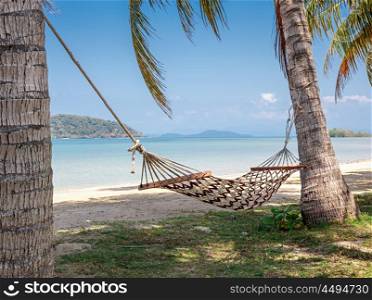 Hammock in the shade of palm trees on a tropical beach