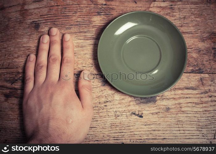 Hand and coffee cup saucer at a table