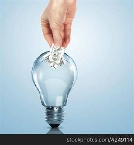 Hand and money inside an electric light bulb