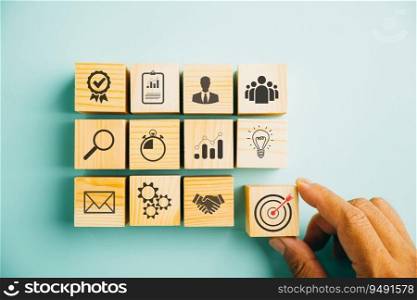 Hand arranging wood block stacking on a blue background, symbolizing the business strategy and action plan. Targeting the business concept and showcasing growth and success. Copy space included.