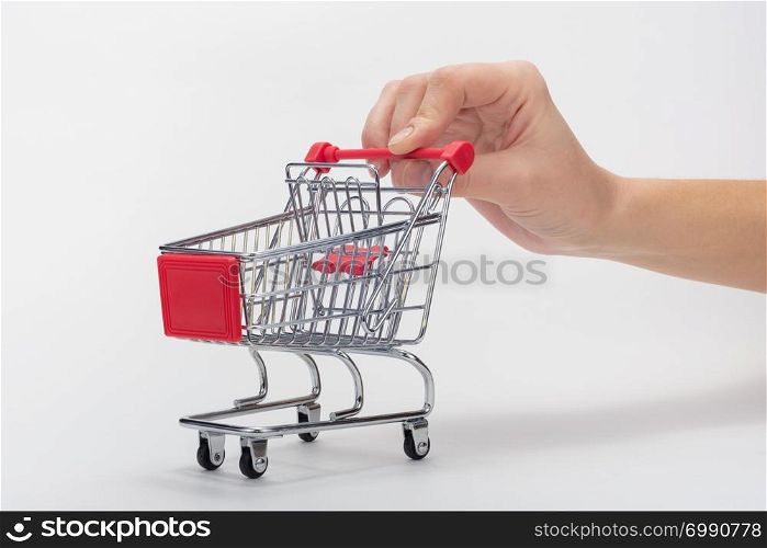 Hand carries empty grocery cart, white background