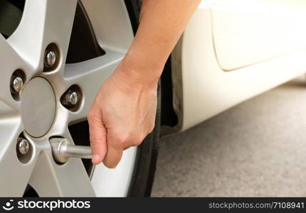 Hand changing tire with car wrench.