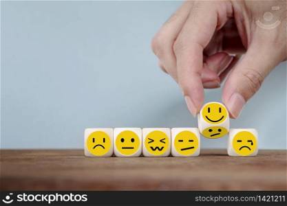 Hand Changing with smile emoticon icons face on Wooden Cube , hand flipping unhappy turning to happy symbol
