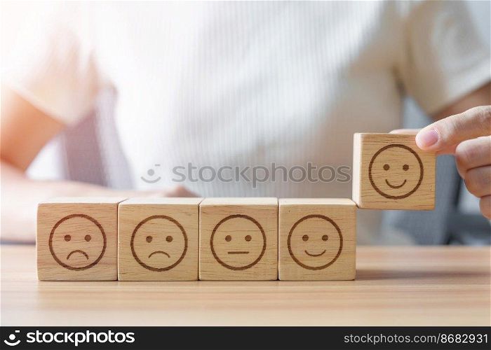 Hand choosing smile face from Emotion block.  customer review, good experience, positive feedback, satisfaction, survey, rating service, assessment, mood, world mental health day concept