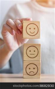 Hand choosing smile face from Emotion block for customer review, good experience, positive feedback, satisfaction, survey, evaluation, assessment, mood, world mental health day concept