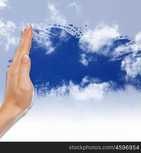 Hand cleaning window with blue sky and white clouds