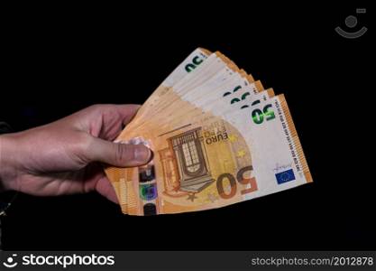 Hand counting holding and showing euro money or giving money. World money concept, 50 EURO banknotes EUR currency isolated on black with copy space. Concept of rich people, saving or spending money