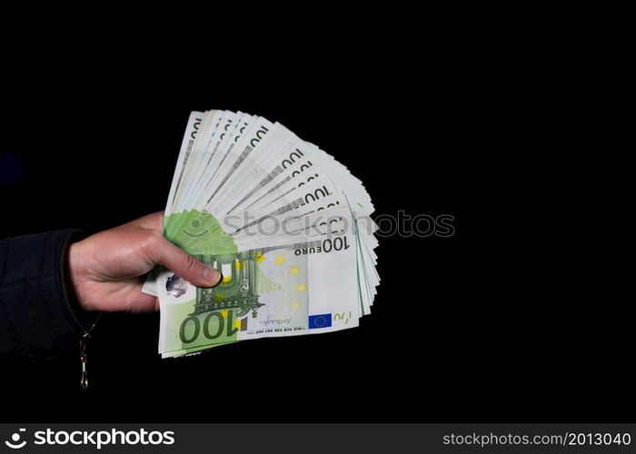 Hand counting holding and showing euro money or giving money. World money concept, 100 EURO banknotes EUR currency isolated on black with copy space. Concept of rich people, saving or spending money