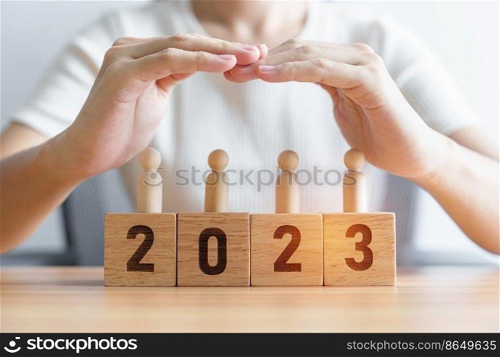 hand cover wooden man employees with 2023 Year block. Insurance, protect, People, Human resource management, leadership and New year Concepts