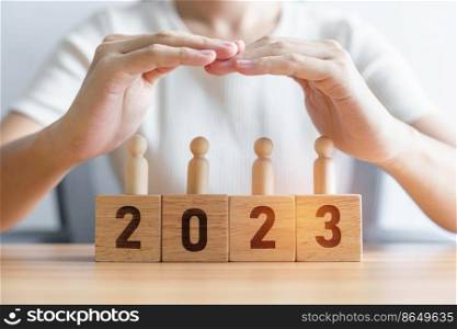 hand cover wooden man employees with 2023 Year block. Insurance, protect, People, Human resource management, leadership and New year Concepts