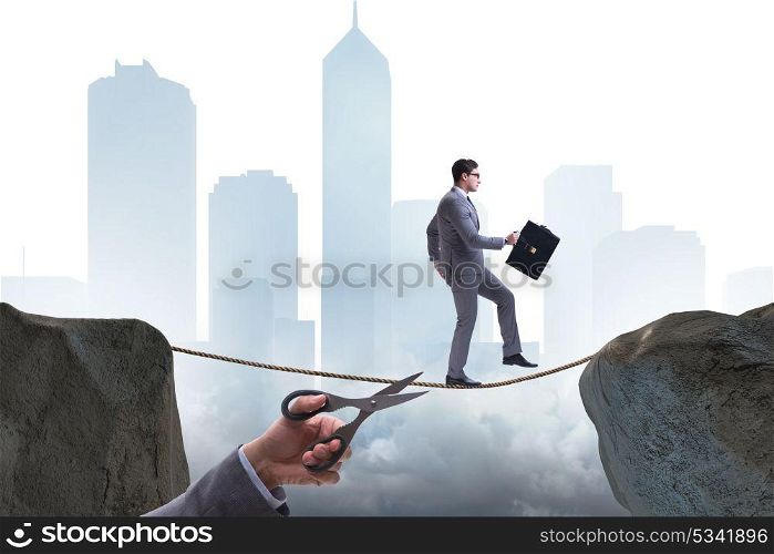 Hand cutting the rope under businessman tightrope walker