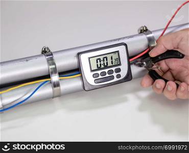 Hand cutting wire on pipe bomb with an lcd clock timer to trigger detonation on white background