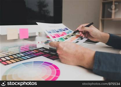 Hand designer choosing colors for doing graphic on laptop.