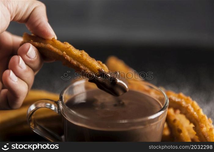 hand dipping fried churros chocolate