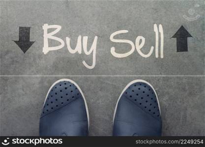 Hand drawn BUY or SELL design word on front of business man feet as concept