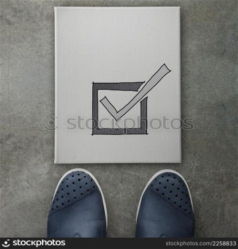 Hand drawn check mark icon on canvas board on front of business man feet as concept
