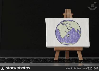 hand drawn globe with social network diagram on canvas and wooden easel on laptop computer as concept