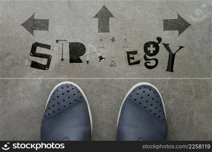 Hand drawn STRATEGY design word on front of business man feet as concept