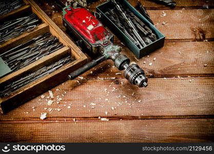 Hand drill with various drills. On a wooden background. High quality photo. Hand drill with various drills.