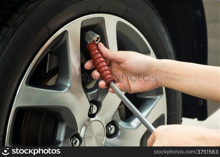 Hand fill air into a car tire.