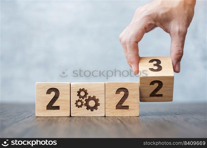 hand flip 2022 to 2023 block with gear icon. Business Process, Team, teamwork, Goal, Target, Resolution, strategy, plan, Action, motivation, change, brainstorm and New Year start concepts