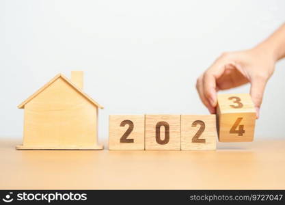 hand flip 2023 to 2024 block with house model. real estate, Home loan, tax, investment, financial, savings and New Year Resolution concepts