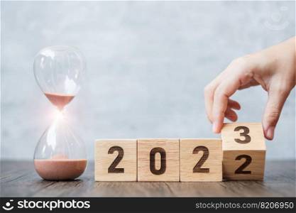 hand flip block 2022 to 2023 text with hourglass on table. Resolution, time, plan, goal, motivation, reboot, countdown  and New Year holiday concepts