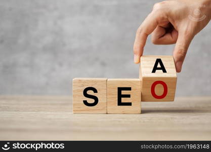 Hand flip SEA to SEO text wooden cube blocks on table background. Search Engine Optimization, Advertising, Idea, Strategy, marketing, Keyword and Content concept