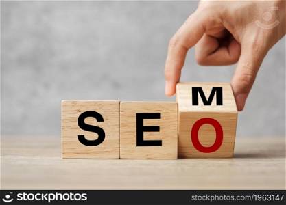 Hand flip SEM to SEO text wooden cube blocks on table background. Search Engine Optimization, Advertising, Idea, Strategy, marketing, Keyword and Content concept