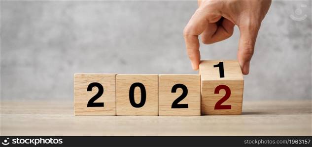 hand flipping block 2021 to 2022 text on table. Resolution, strategy, plan, goal, motivation, reboot, business and New Year holiday concepts