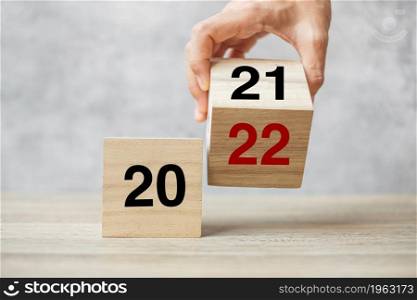 hand flipping block 2021 to 2022 text on table. Resolution, strategy, plan, goal, motivation, reboot, business and New Year holiday concepts